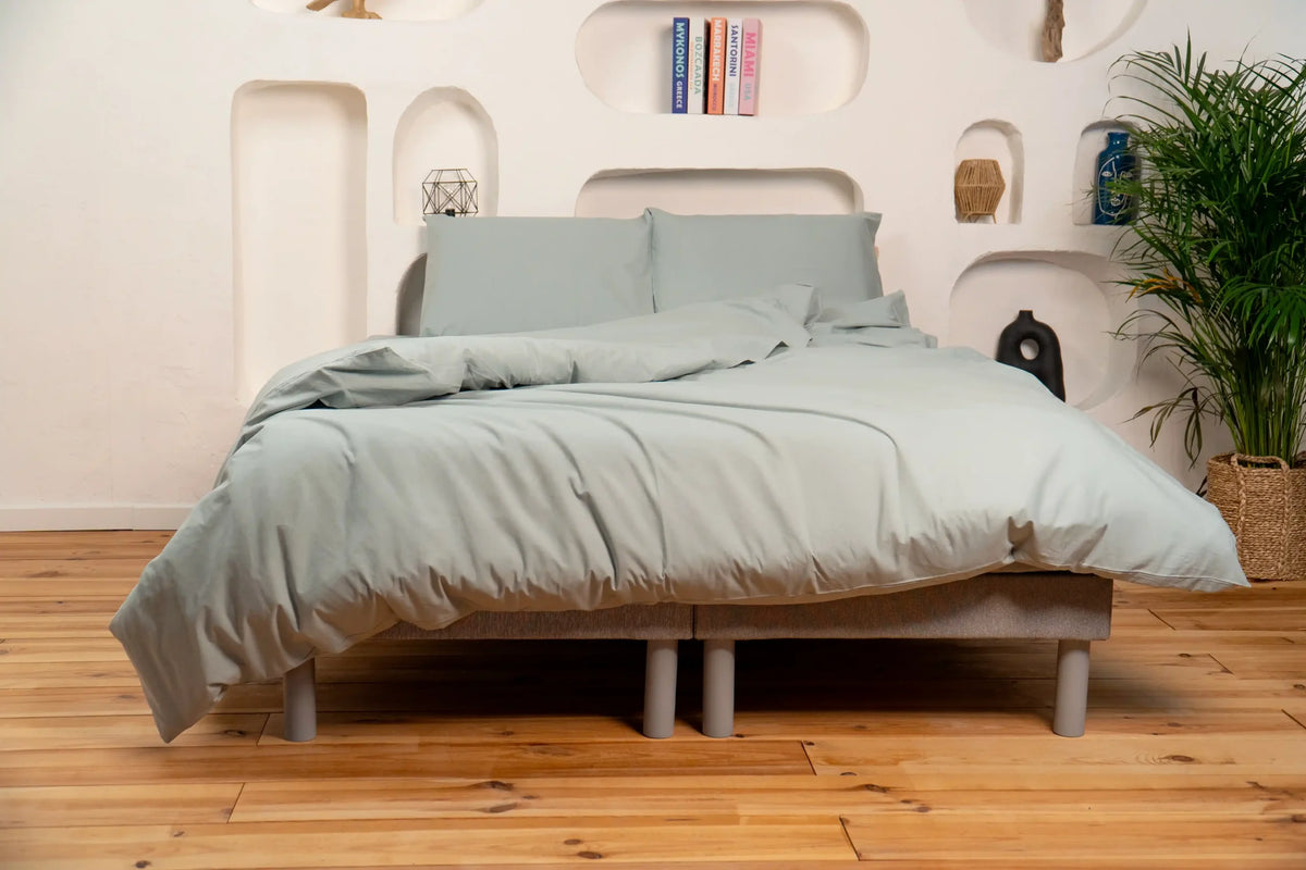 Lit avec parure de lit vert sauge dans une chambre