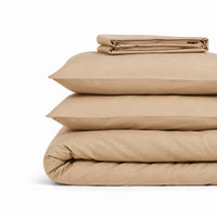 Parure de lit en coton beige pliée : housse de couette, taies et drap housse